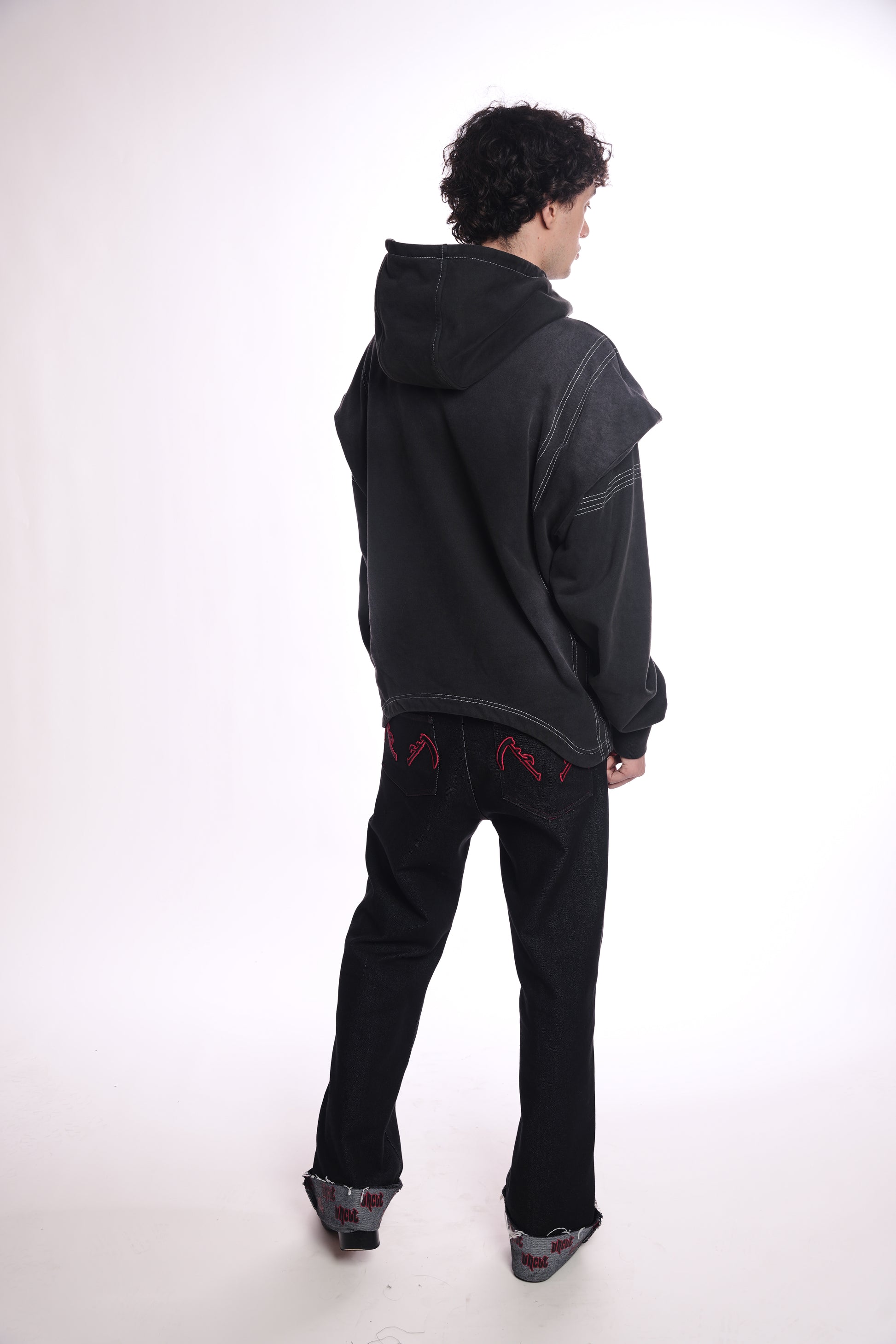 Person wearing a black hoodie OGP zip up  and pants on a white background