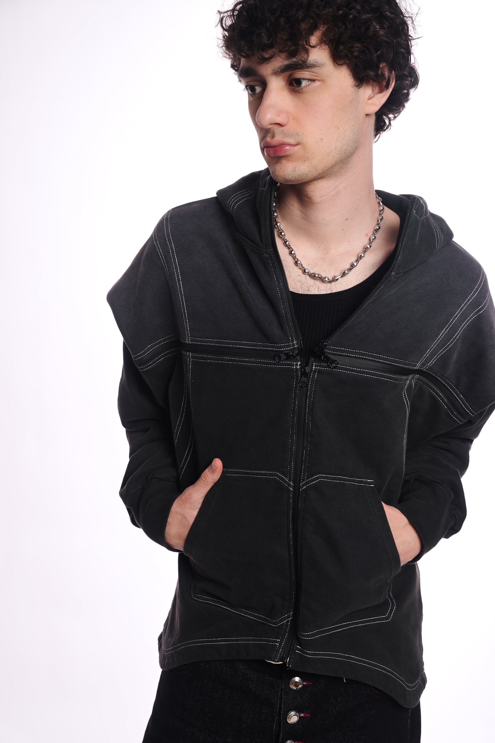 Person wearing a black hoodie with white stitching on a white background