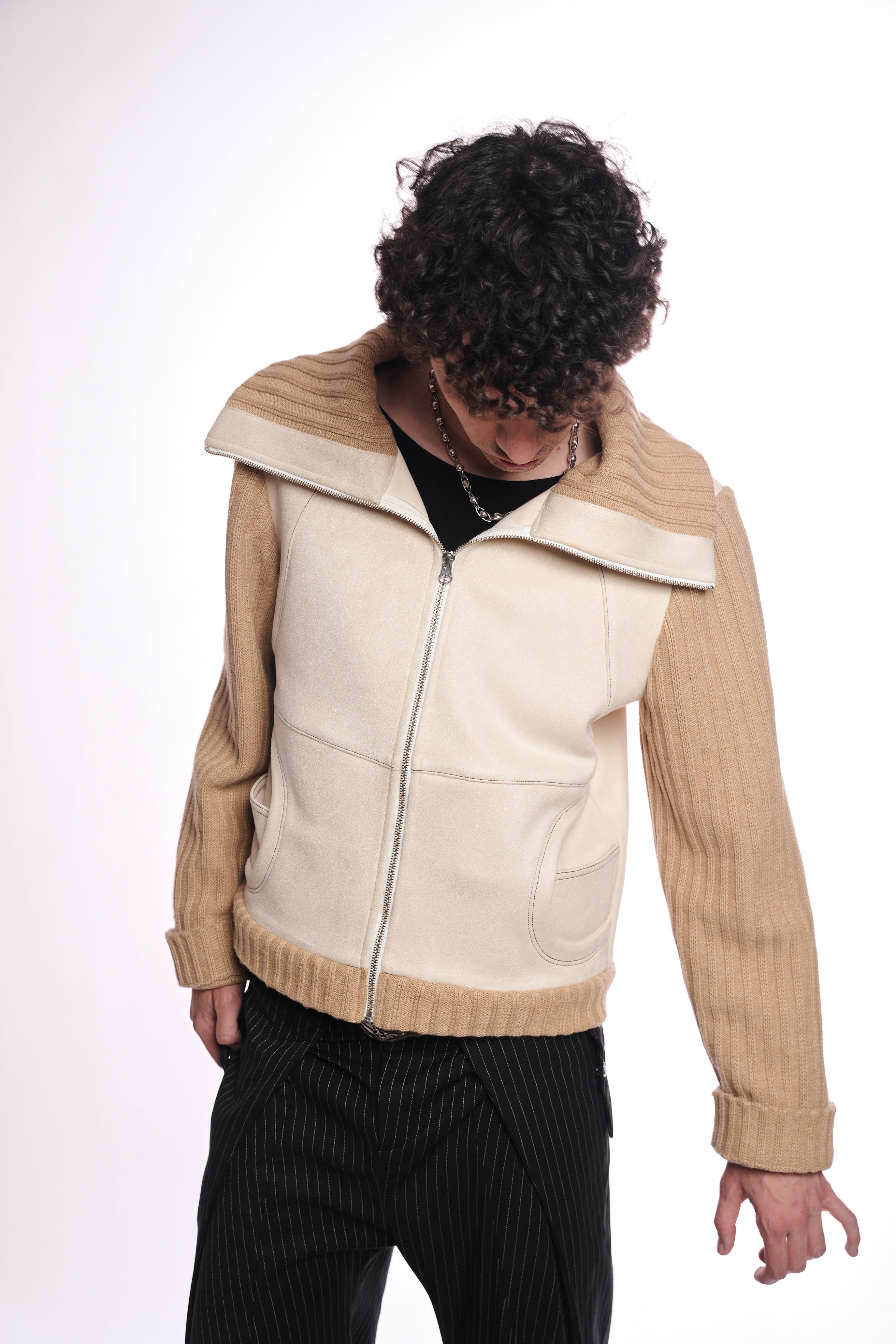 Person wearing a beige and cream jacket on a white background
