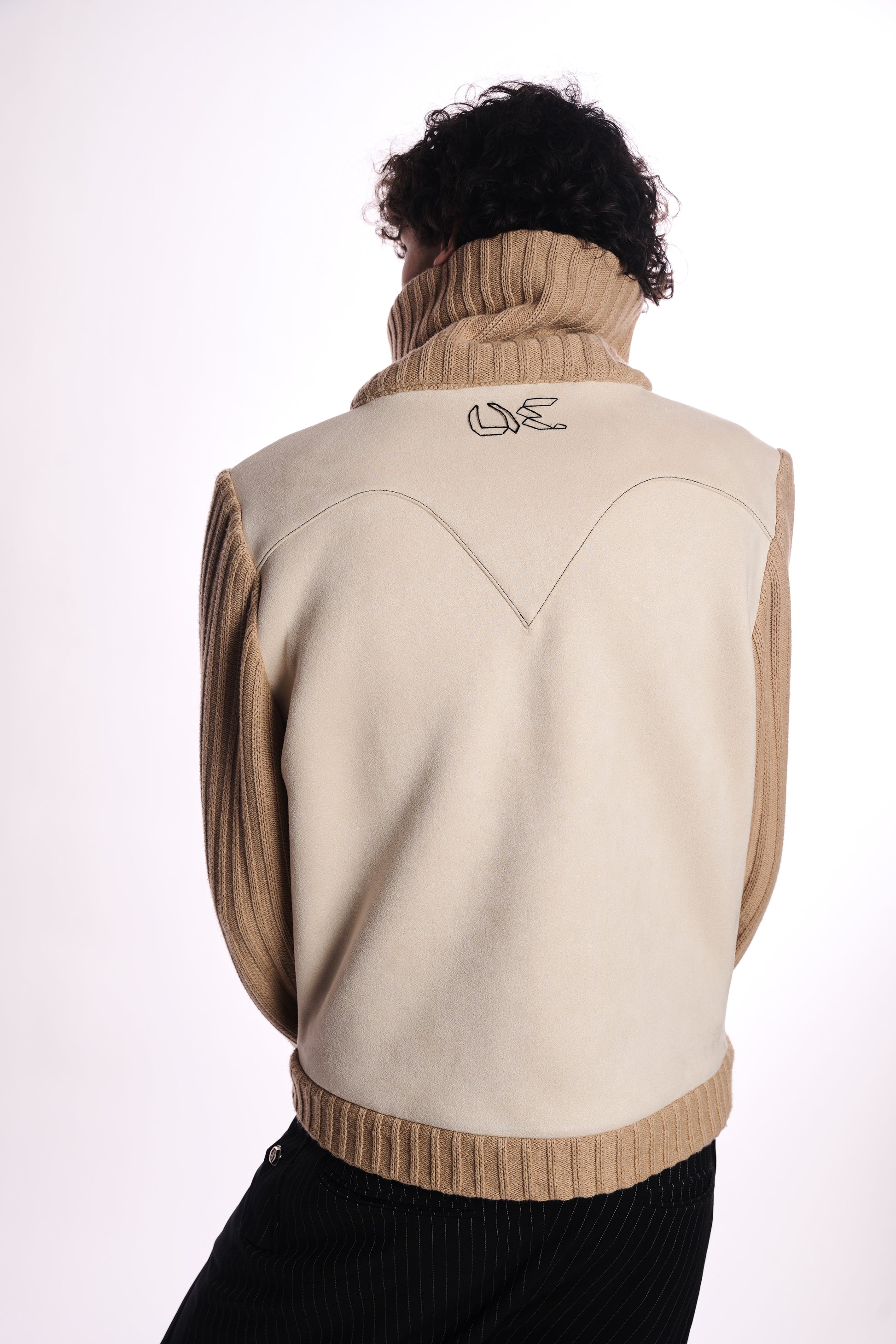 Person wearing a beige vest with thr uncut logo on the back against a white background