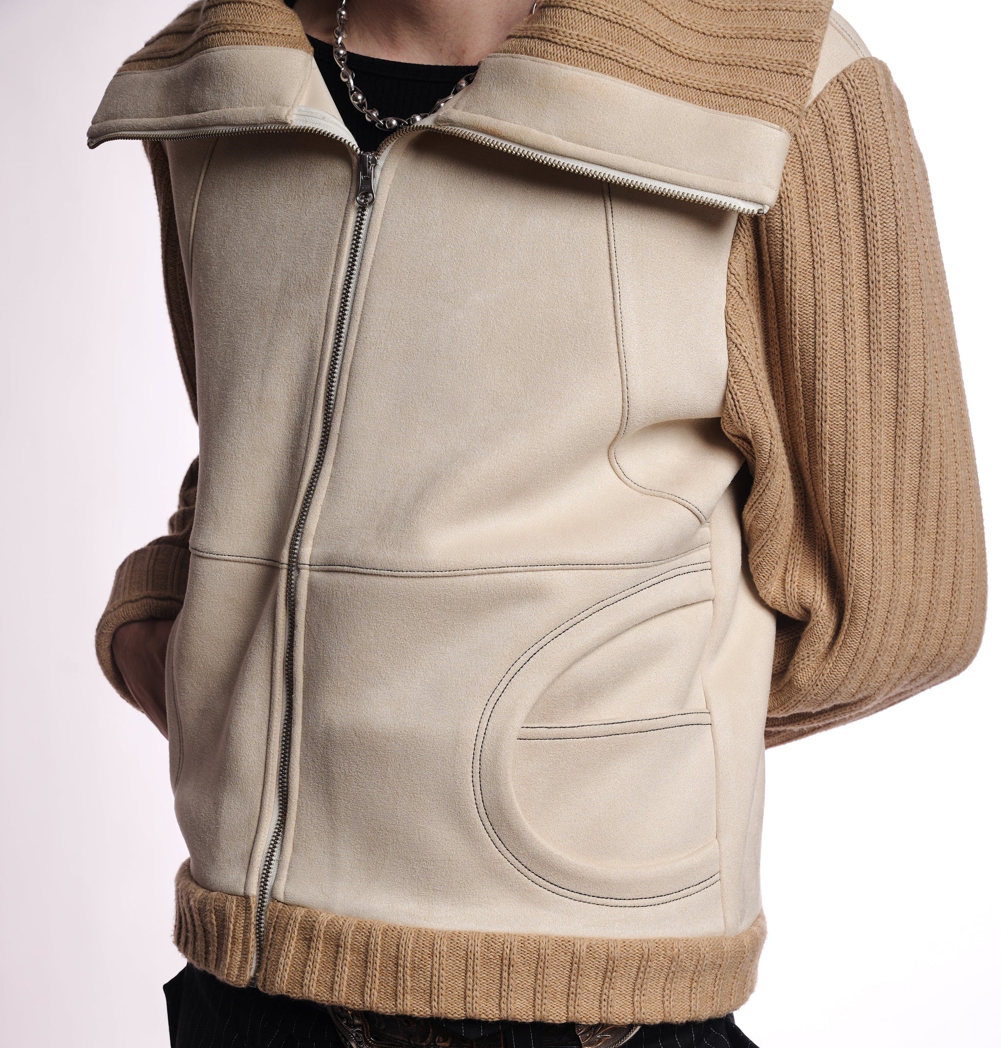Beige zip up with brown trim worn over a sweater on a white background