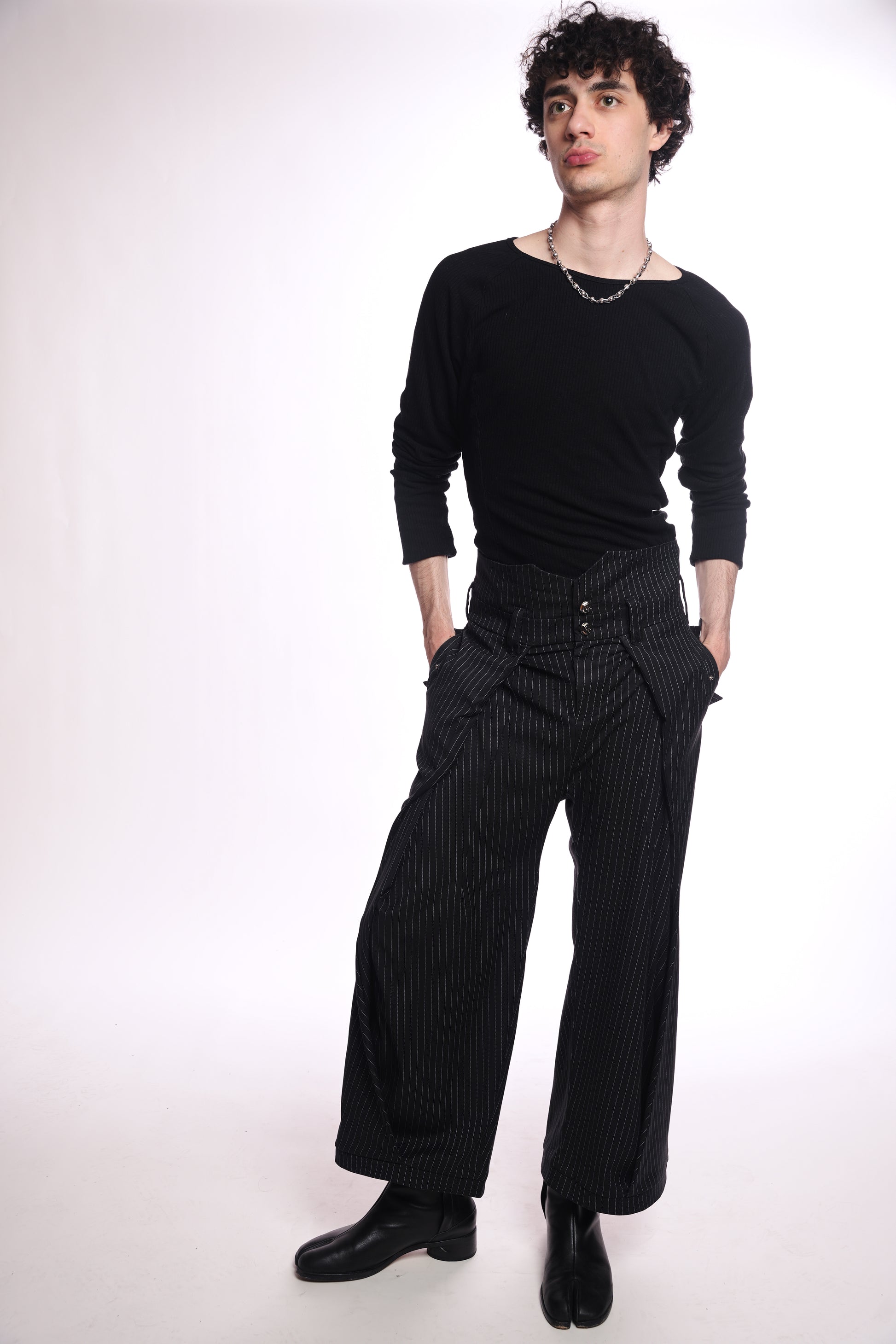 Person wearing a black outfit with wide-leg pants on a white background