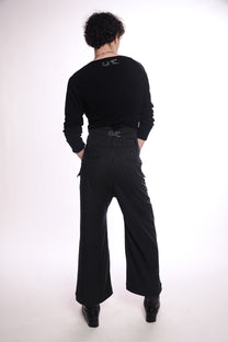 Person wearing a black outfit with wide-leg pants origami pants  on a white background