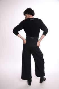 Person wearing a black outfit with wide-leg pants on a white background
