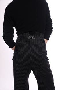 Person wearing a black sweater and pinstripe pants on a white background